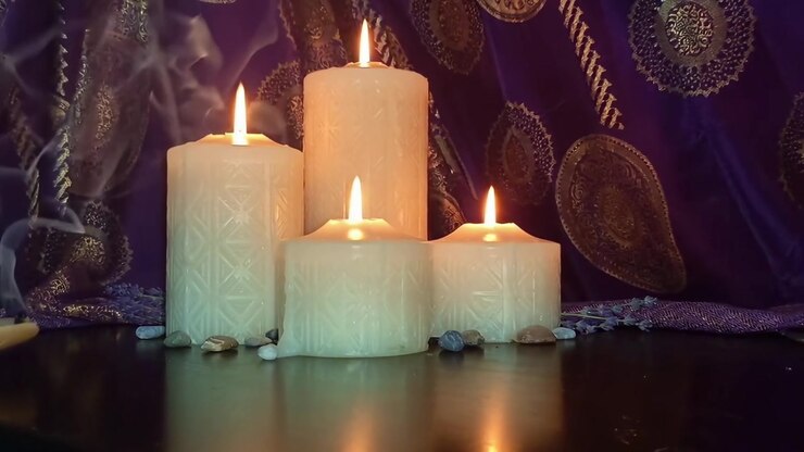 Tre candele accese con fumo su uno sfondo di tessuto viola