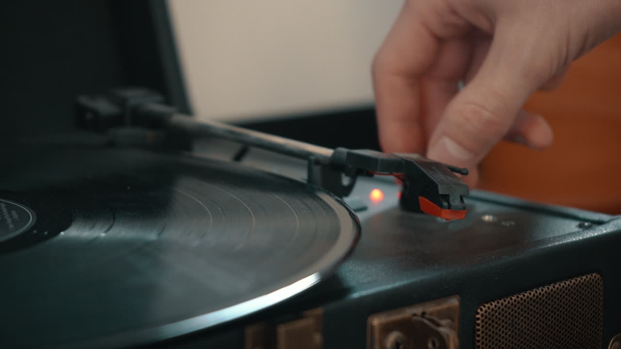 A hand takes the needle off of a spinning vinyl record.