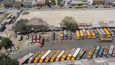 Luftaufnahme,-Drohnen-Zeitrafferaufnahme-Von-Bussen,-Die-Von-Einem-Parkplatz-In-Guatemala-Abfahren,-4k