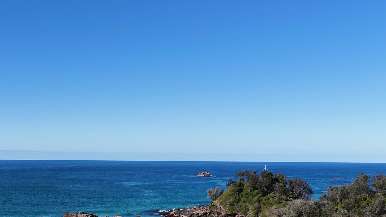 Ampia inquadratura panoramica dell'Oceano Pacifico turchese e di un promontorio roccioso a South West Rocks, Australia.