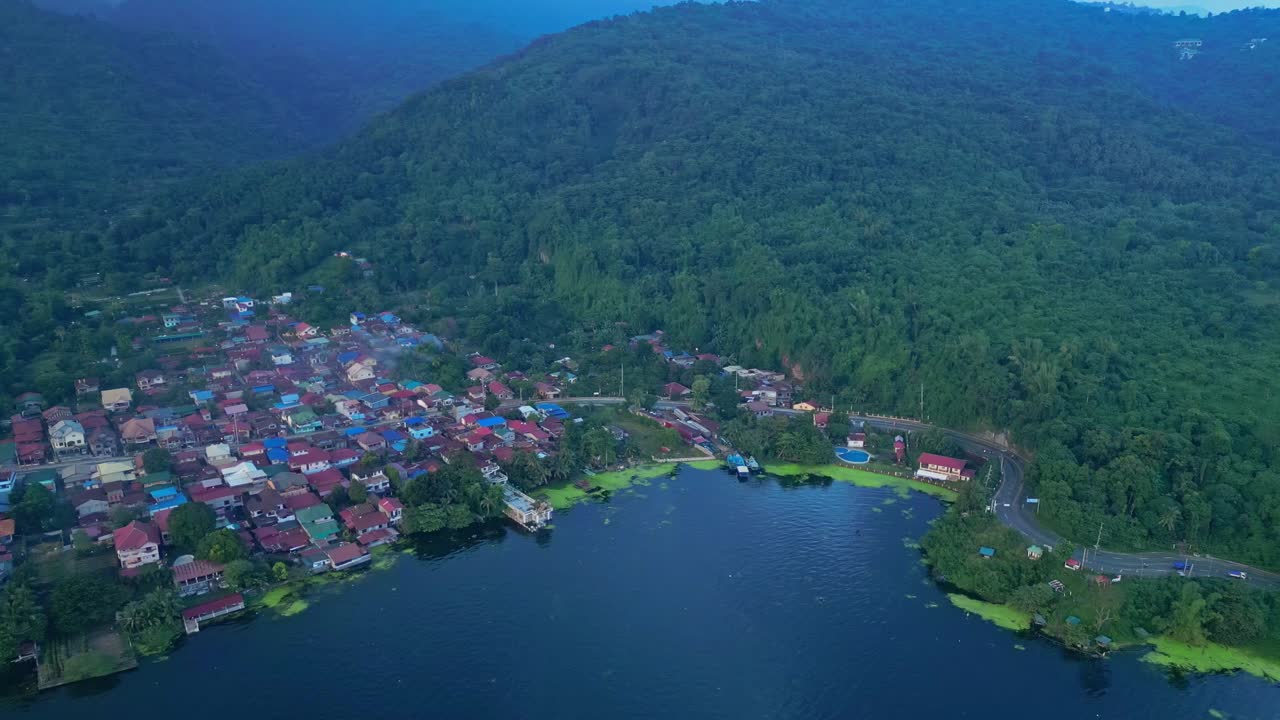 A pull-out aerial of Talisay town and forested hillside retreat lining the calm shore of Taal Lake in Batangas, Philippines