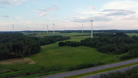 wind turbines in green countryside with highway in foreground