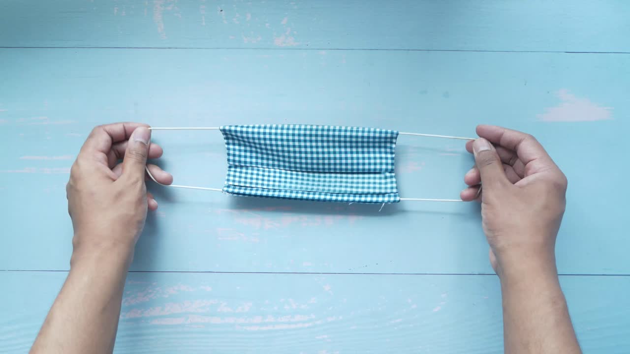 파란색 체크 얼굴 마스크를 들고 있는 사람