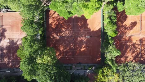 climb with drone camera down showing beautiful tennis courts hidden in the middle of many trees