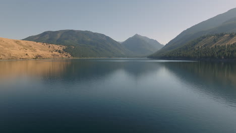 aerial view over mountain lake slowly lowering down to water level