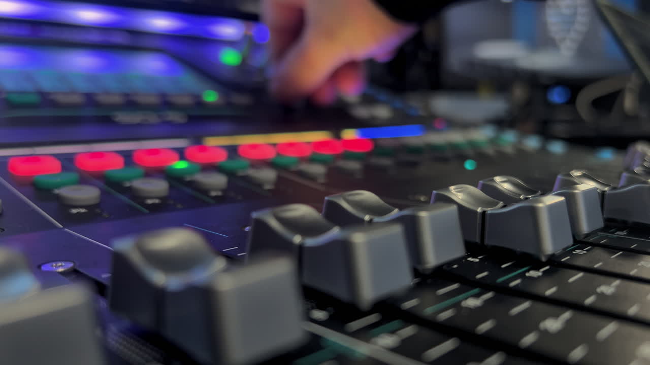 Close-up of an audio mixing console with moving faders and blinking lights during live event production. Professional sound engineering workflow in an event and broadcast environment