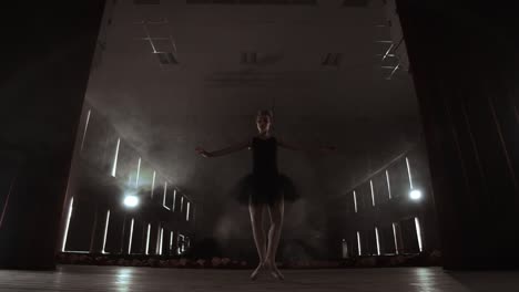 ballerina is practicing her moves in dark studio. young girl dancing with air white dress tutu, spinning around and smiling. gracefulness and tenderness in every movement.