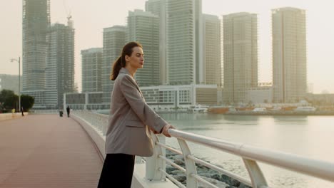 mujer junto al agua en una ciudad al atardecer