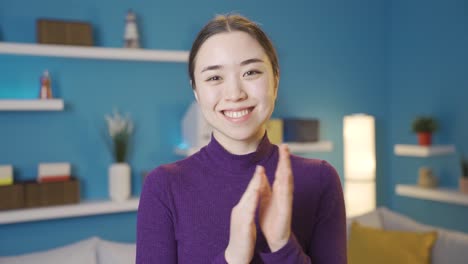 Asian-woman-happily-clapping-while-looking-at-camera.