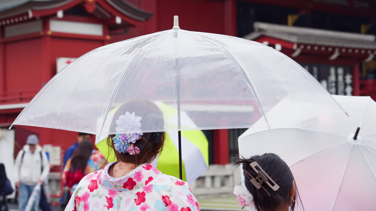 Slow motion of people holding umbrellas walking through the Asakusa, Senso-ji on a rainy day. Tokyo