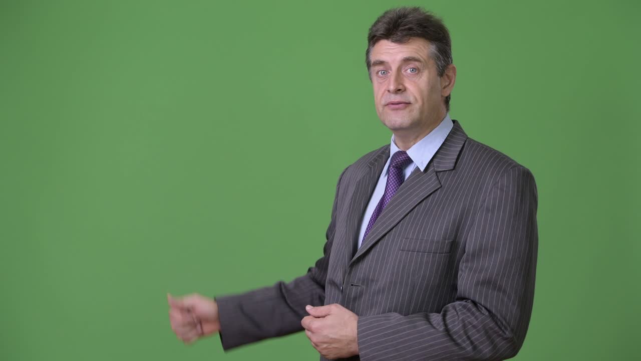 Mature handsome businessman against green background