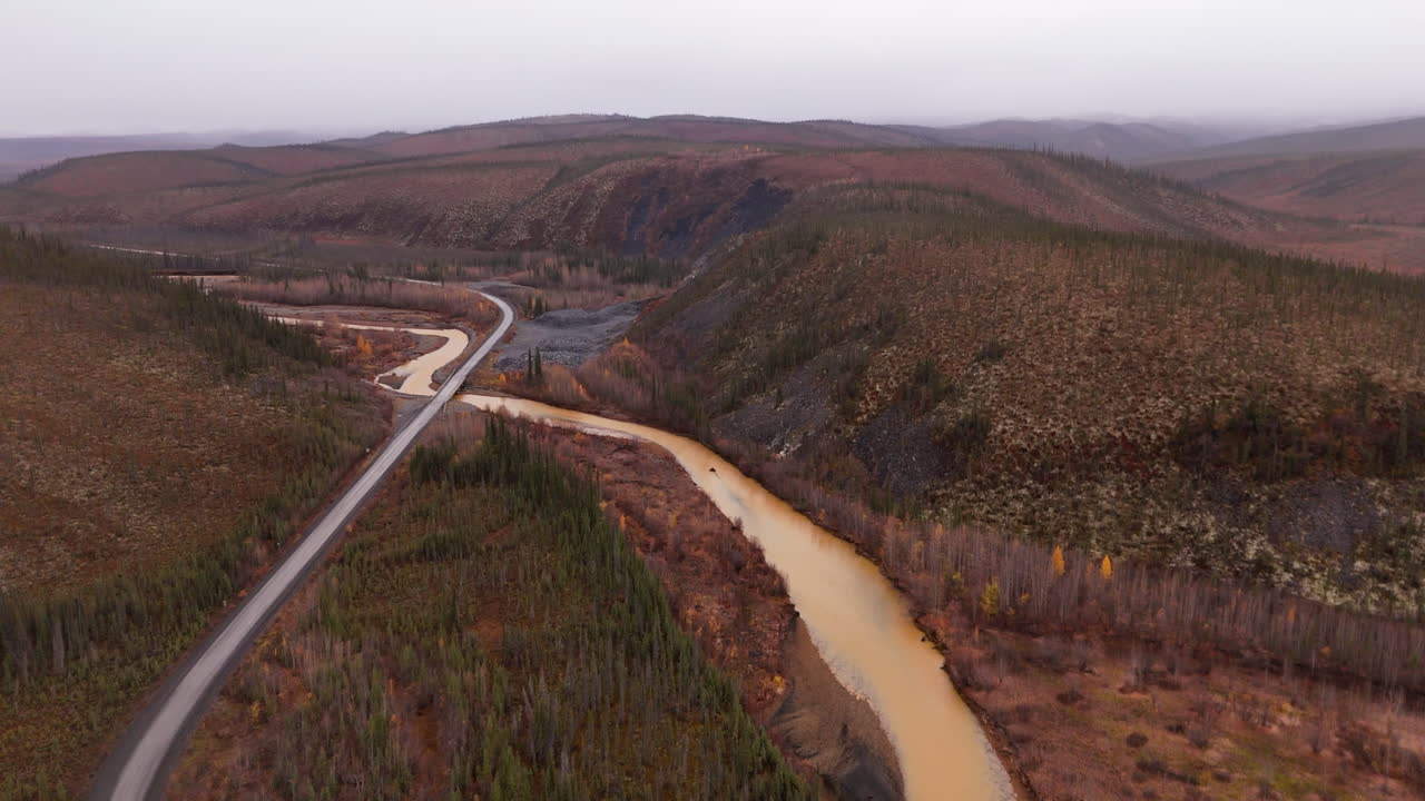Dempster Highway Across Ogilvie River In Yukon Territory, Northwestern Canada. aerial pullback shot