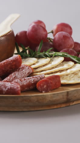 crispy biscuits, tomatoes, grapes and bowl of cheese on wooden board