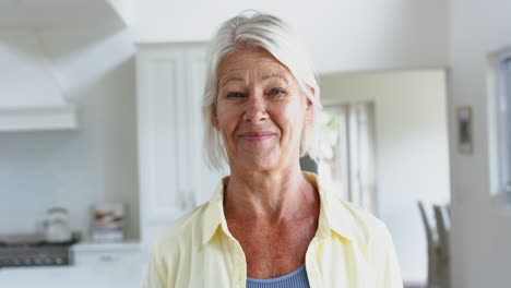 Happy-caucasian-senior-woman-standing-and-laughing-in-sunny-room-at-home,-slow-motion