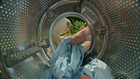 woman loading washing machine with clothes, dog watching