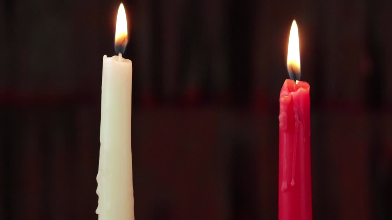 Due candele accese, bianche e rosse, steadycam