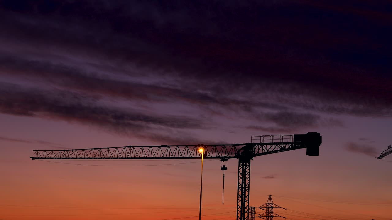 nubes negras se deslizan suavemente al atardecer sobre una grúa de construcción
