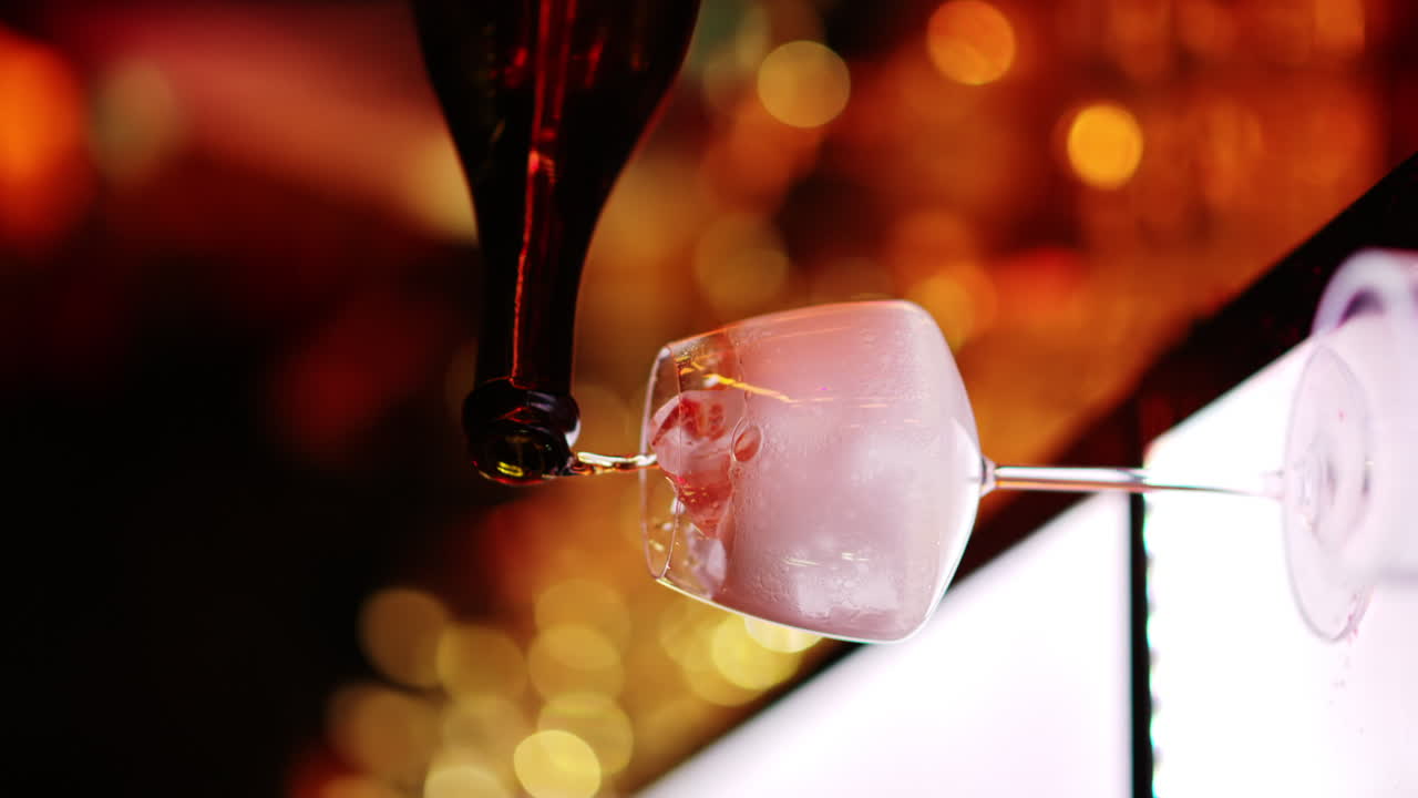 Barman making cocktails with white sparkling wine at the bar at night with red neon lights, slow motion vertical screen
