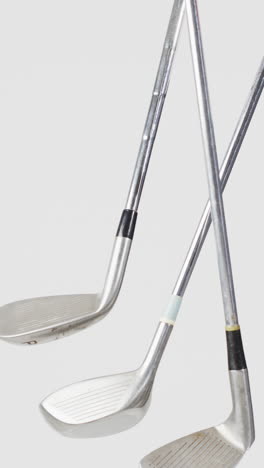 vertical viedo of golf clubs on white background, copy space, slow motion
