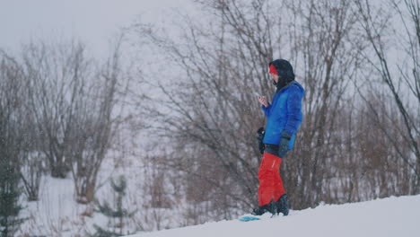 slow motion shot of a snowboarder using a smartphone while driving on a ski slope