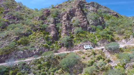 dirt road in rugged desert landscape with truck driving up incline - aerial establishing