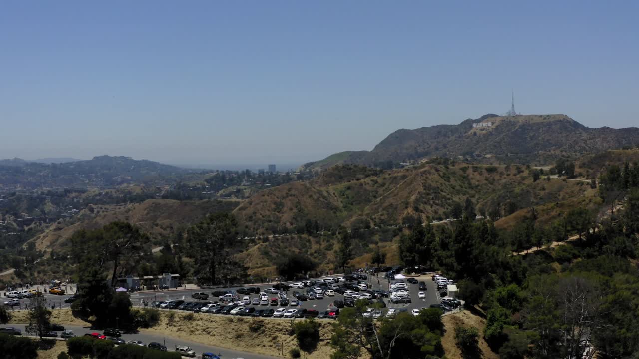 video aereo de un estacionamiento en las montanas de los angeles con el cartel de hollywood a lo lejos