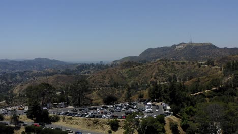 Aerial-video-of-a-parking-lot-in-the-mountains-of-Los-Angeles-with-the-hollywood-sign-in-the-distance