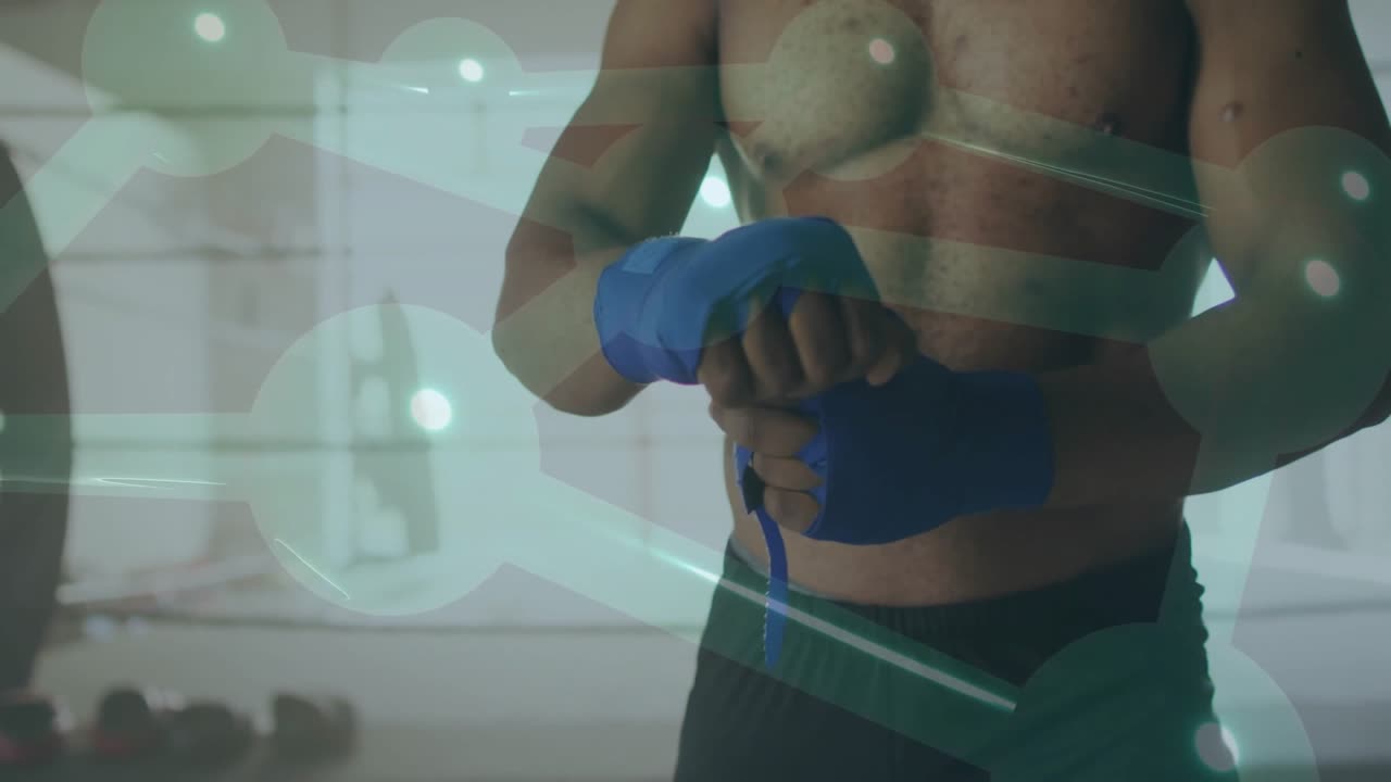 Uomo che prende un bendaggio blu in palestra, avvolgendolo intorno alle nocche preparandosi per l'allenamento.