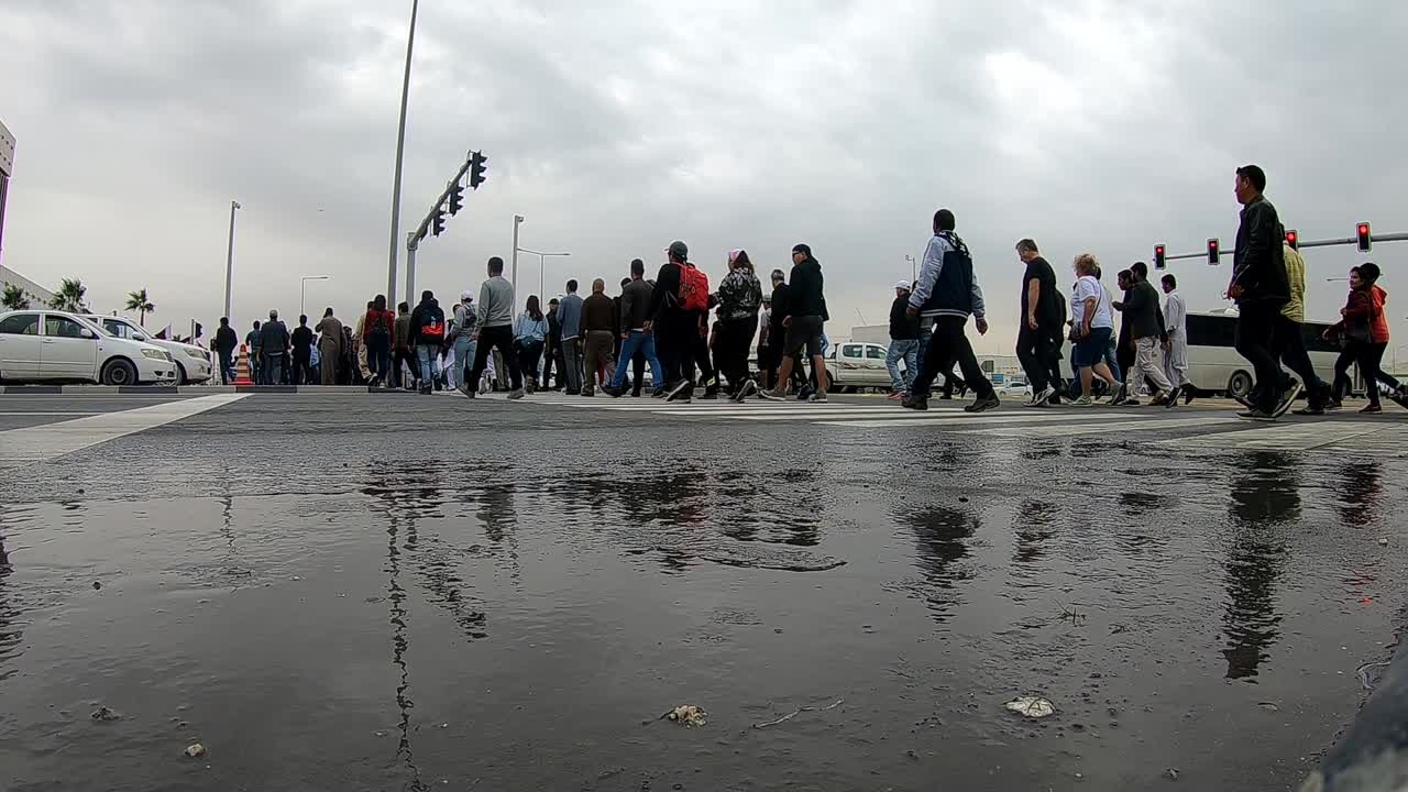 People crossing road using zebra crossing. Doha is capital city of Qatar and major part of population is expatriates here.
