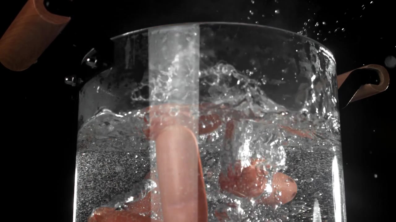 Salsicce che cadono nell'acqua bollente al rallentatore