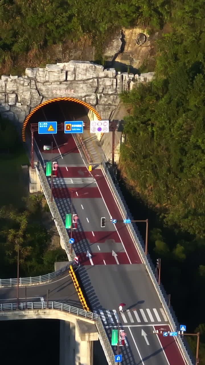 Vertical drone shot following traffic driving to a tunnel, golden hour in China