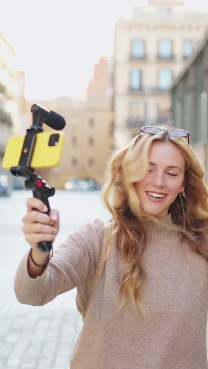 Giovane donna felice che fa vlogging con smartphone e microfono per strada in città