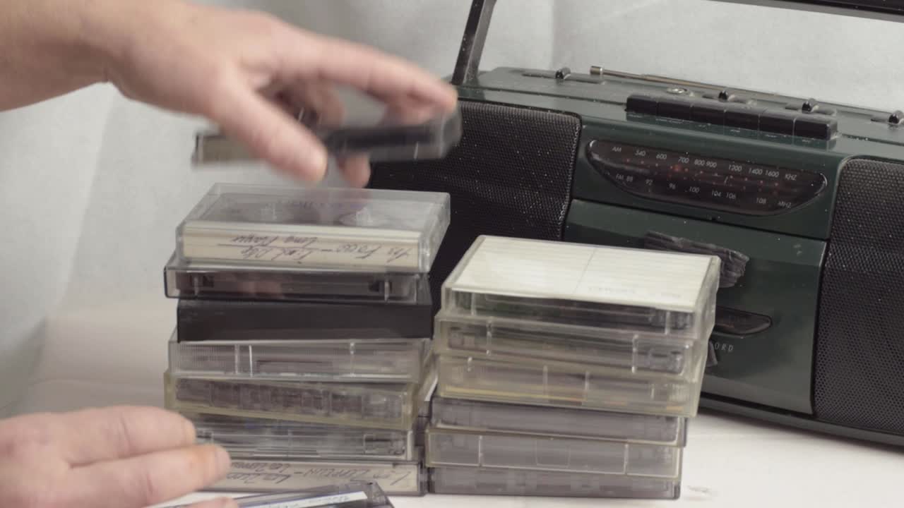 Looking through retro cassette tapes with radio cassette speaker in background