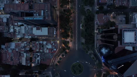 aerial birds eye overhead top down panning view of traffic on wide street with circular crossroad. flying drone following road in evening. mexico city, mexico