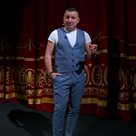 man in suit speaking jokes in microphone standing on stage. funny performance. comedian in good humor speaks to the audience