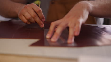 tailor cuts part of leather with cast in craft studio