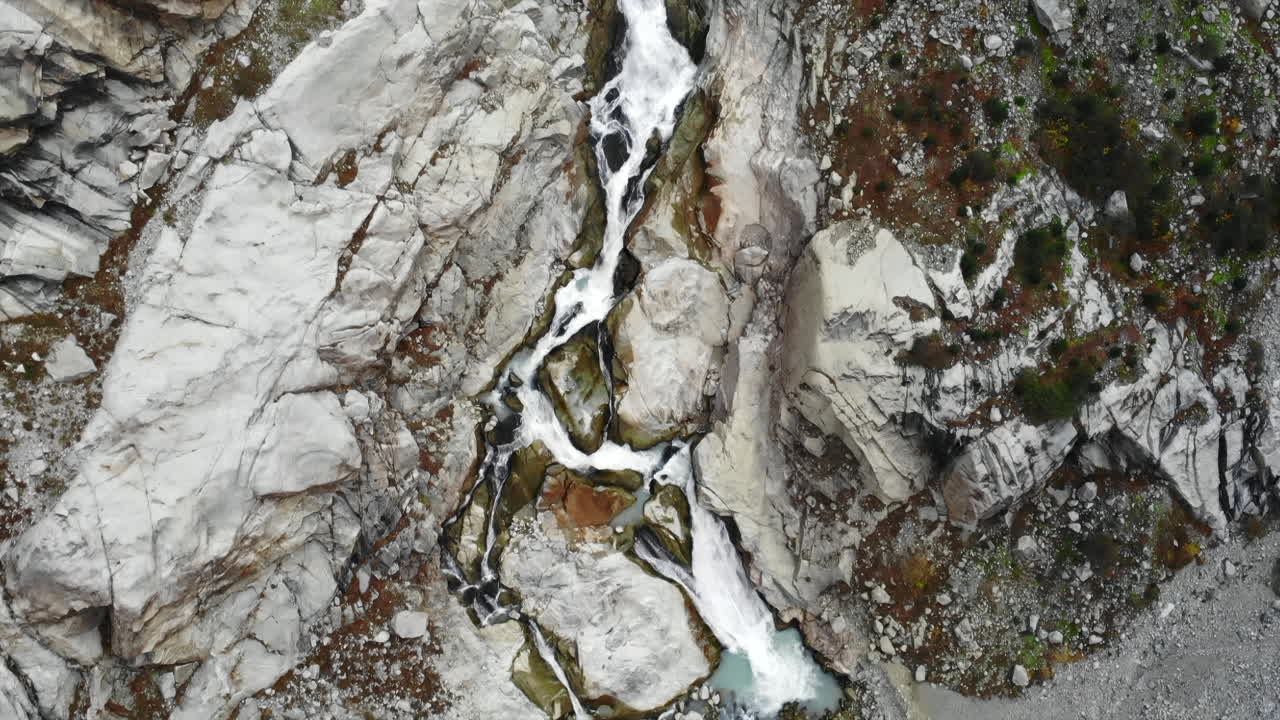 Aerial view of a mountain waterfall flowing through rocks