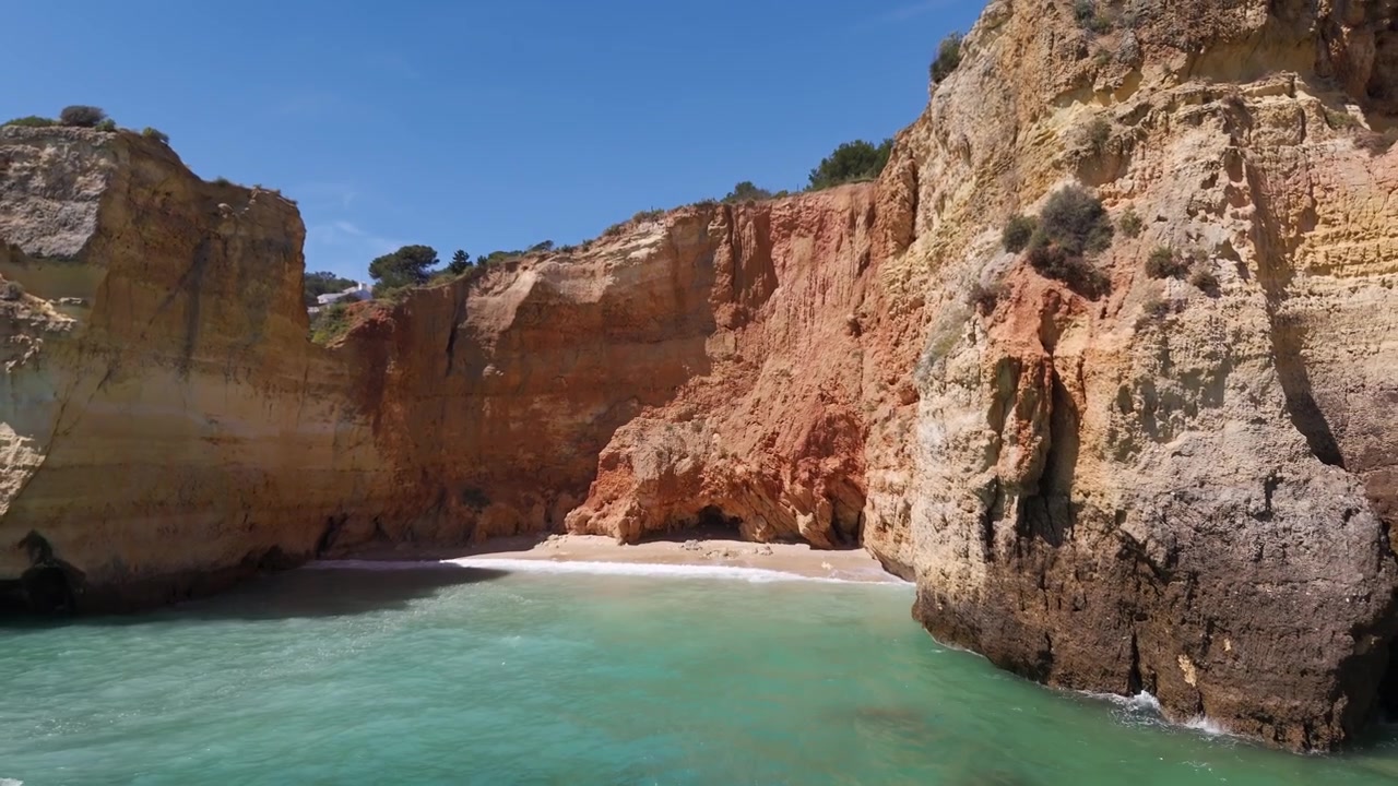 Toma de dron con alejamiento desde una playa apartada, revelando el vasto océano más allá, Algarve, Portugal