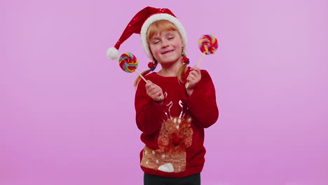 Funny-girl-in-New-Year-sweater-holding-candy-striped-lollipops-hiding-behind-them,-fooling-around