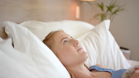 relaxing in bed, woman lying on pillows and looking up, feeling peaceful