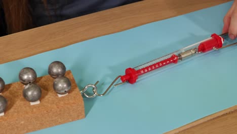 a hand pulls a weighted block using a spring scale on a smooth surface, illustrating friction and force dynamics
