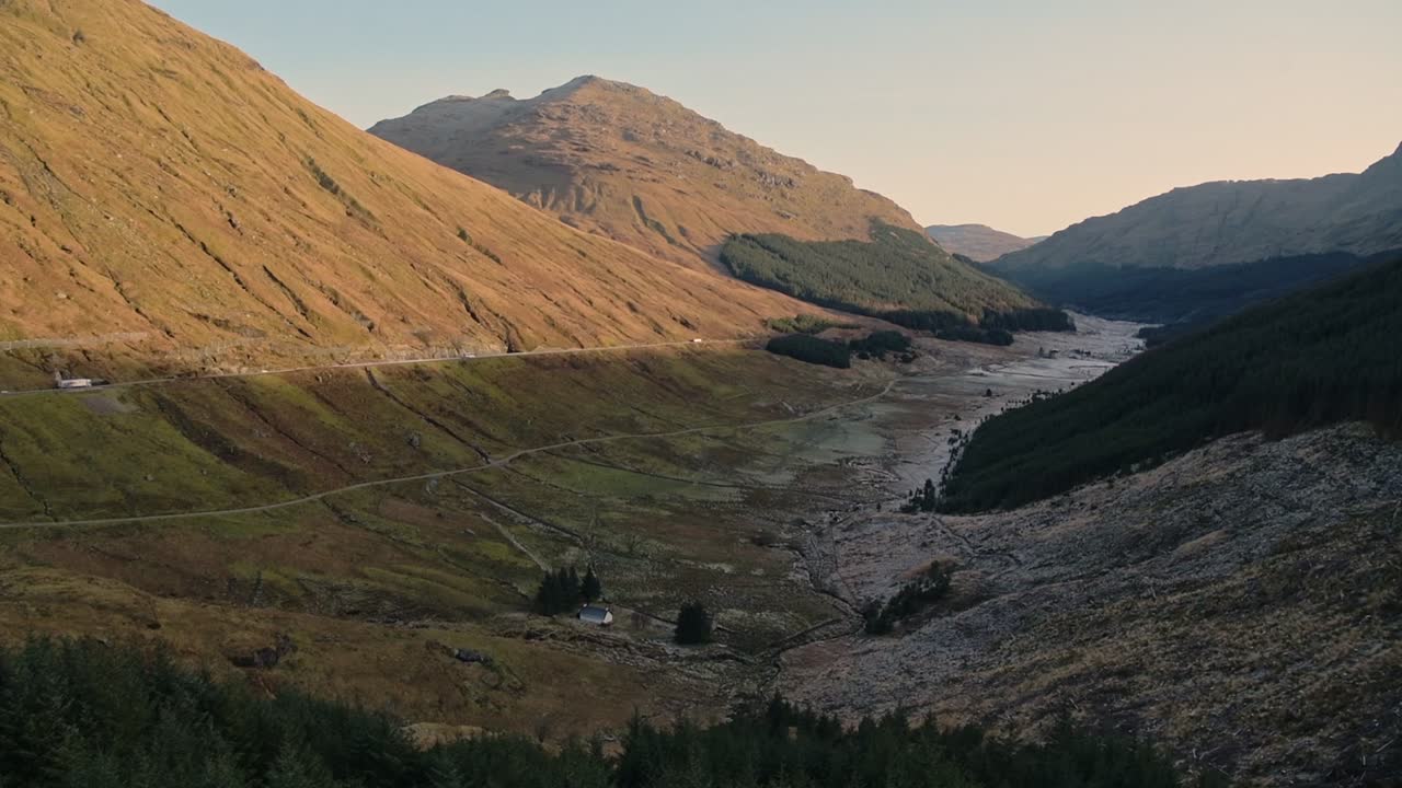 Cars Driving In The Famous Road At The Foot Of The Hills Inside The Great Trossachs Forest National Nature Reserve In Scotland. -wide shot