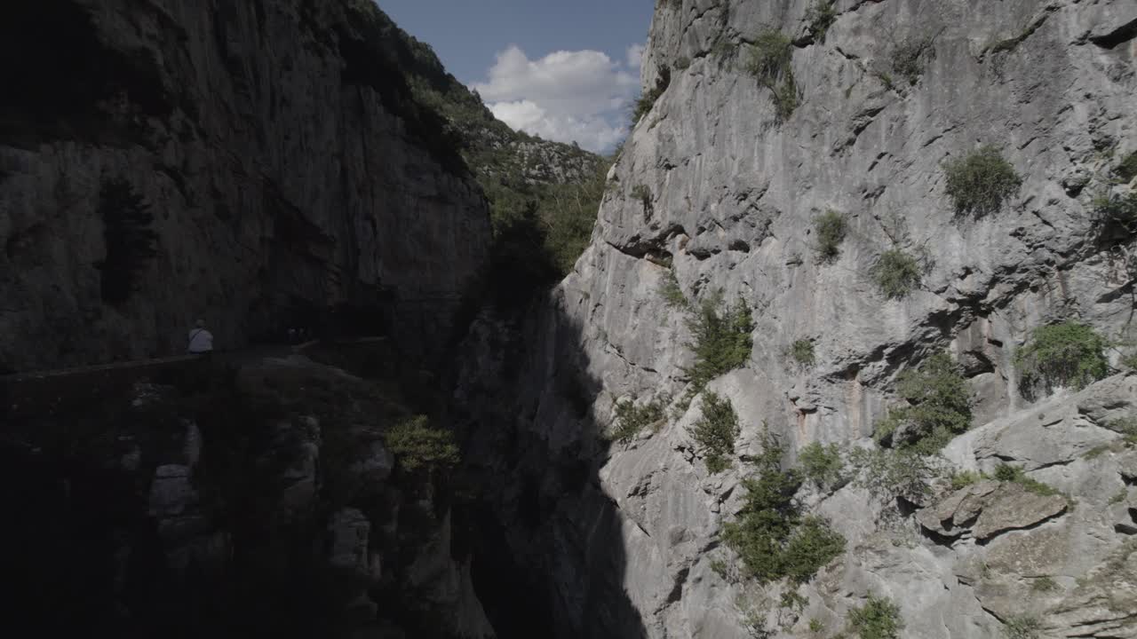 This drone video captures a breathtaking frontal shot along the Boca del Infierno Gorge road in the mountains of the Western Valleys Natural Park, Huesca, Spain. Stunning natural landscapes.