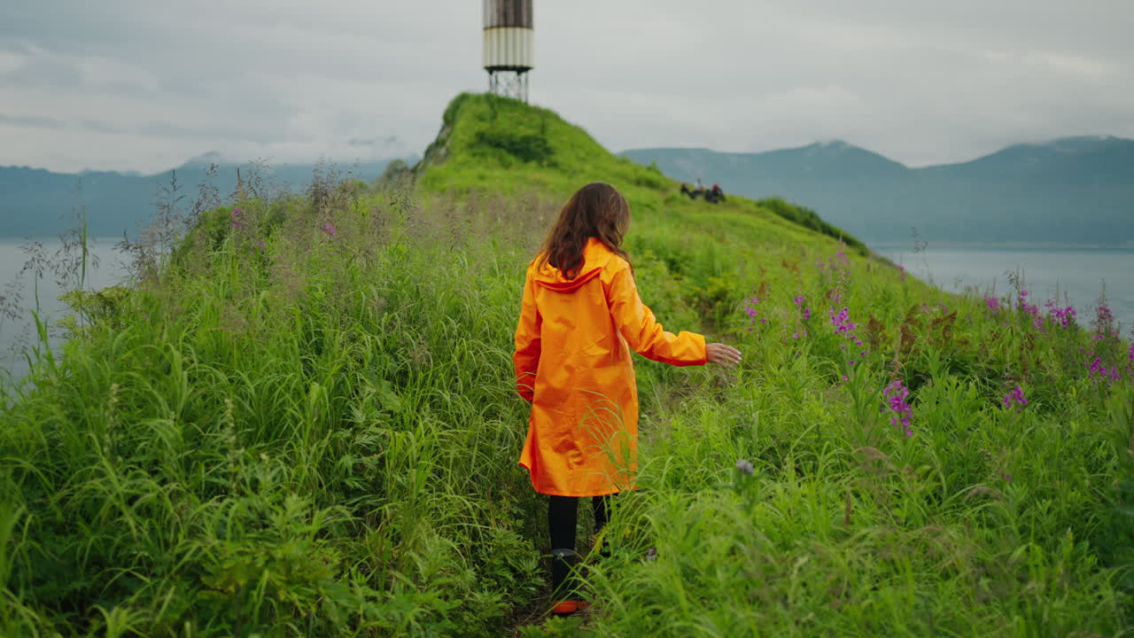 Woman Hiking in Orange Rain Jacket on an Island