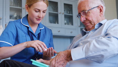 enfermera ayudando a un anciano a organizar la medicación en una visita a casa