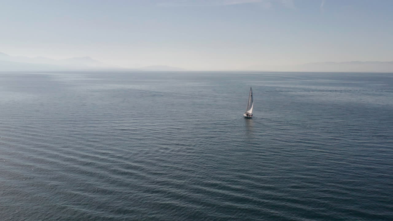 volando hasta un solo barco de vela en un vasto mar vacío
