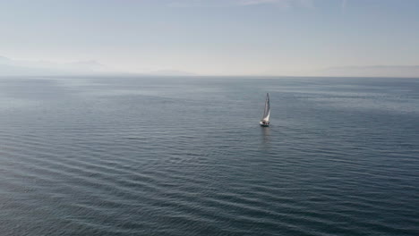 flying up to single sail boat on a vast empty sea