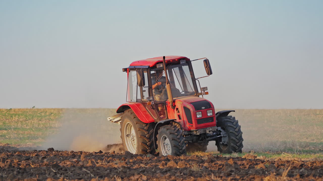 Tractor plows a field. Close up of tractor cultivating field