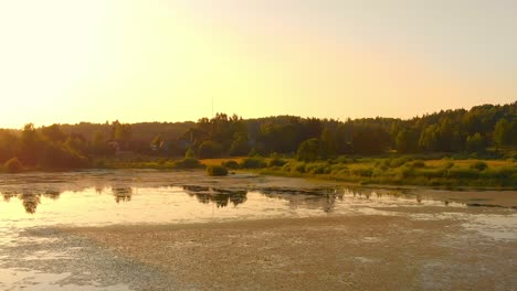 Sich-Schnell-Bewegende-Drohnenbewegung-über-Einem-Natürlichen-See-In-Der-Nähe-Von-Wäldern-Während-Des-Sonnenuntergangs