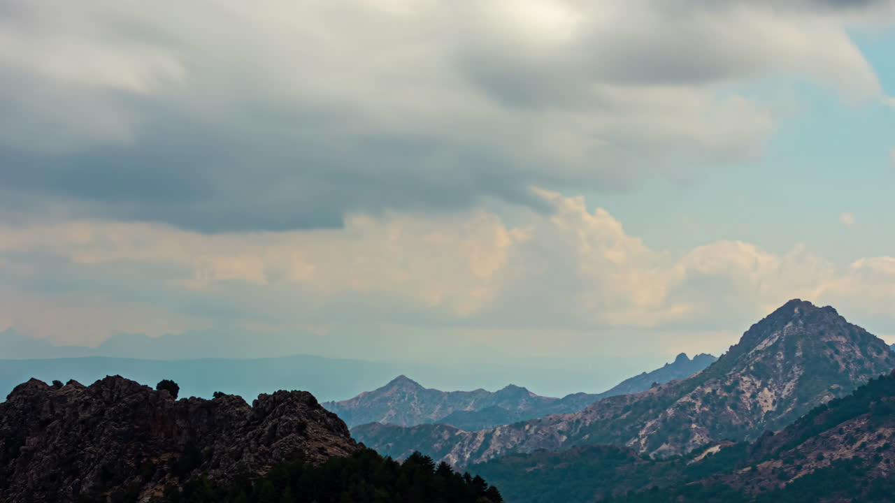 구름이 가득한 하늘의 산악 풍경은 평온과 광활한 자연을 암시합니다.